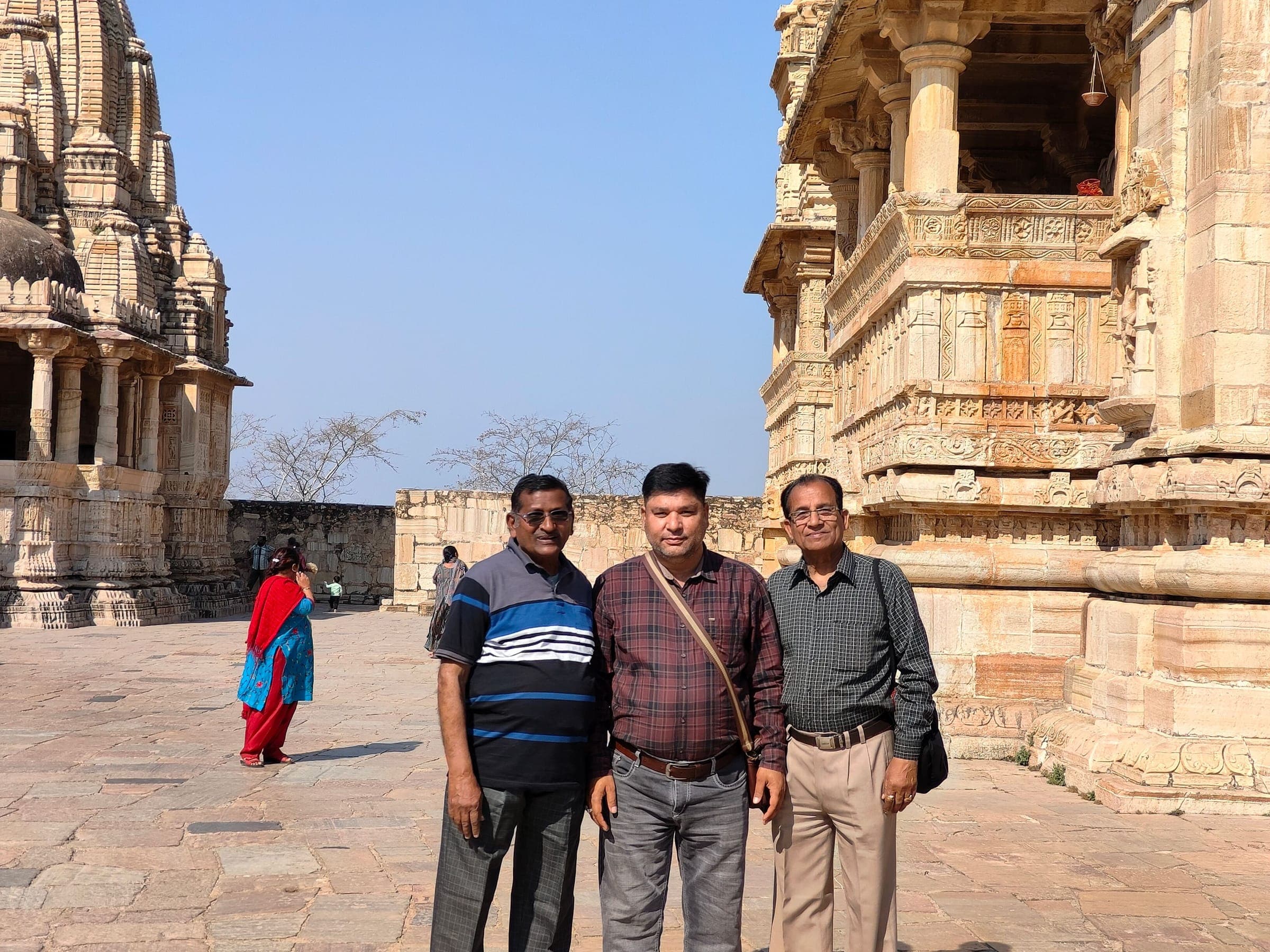 Three travellers standing between carved stone temples at Chittorgarh Fort