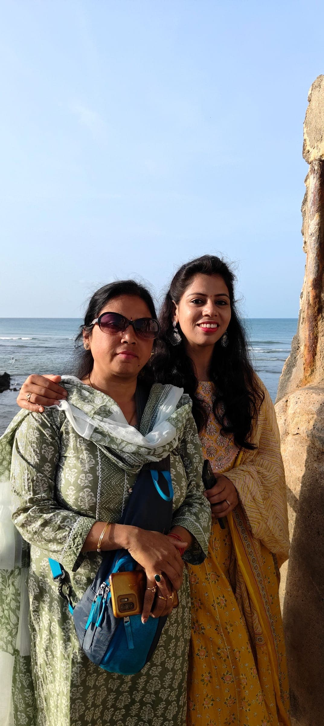 Two travellers standing together by the sea on a bright morning