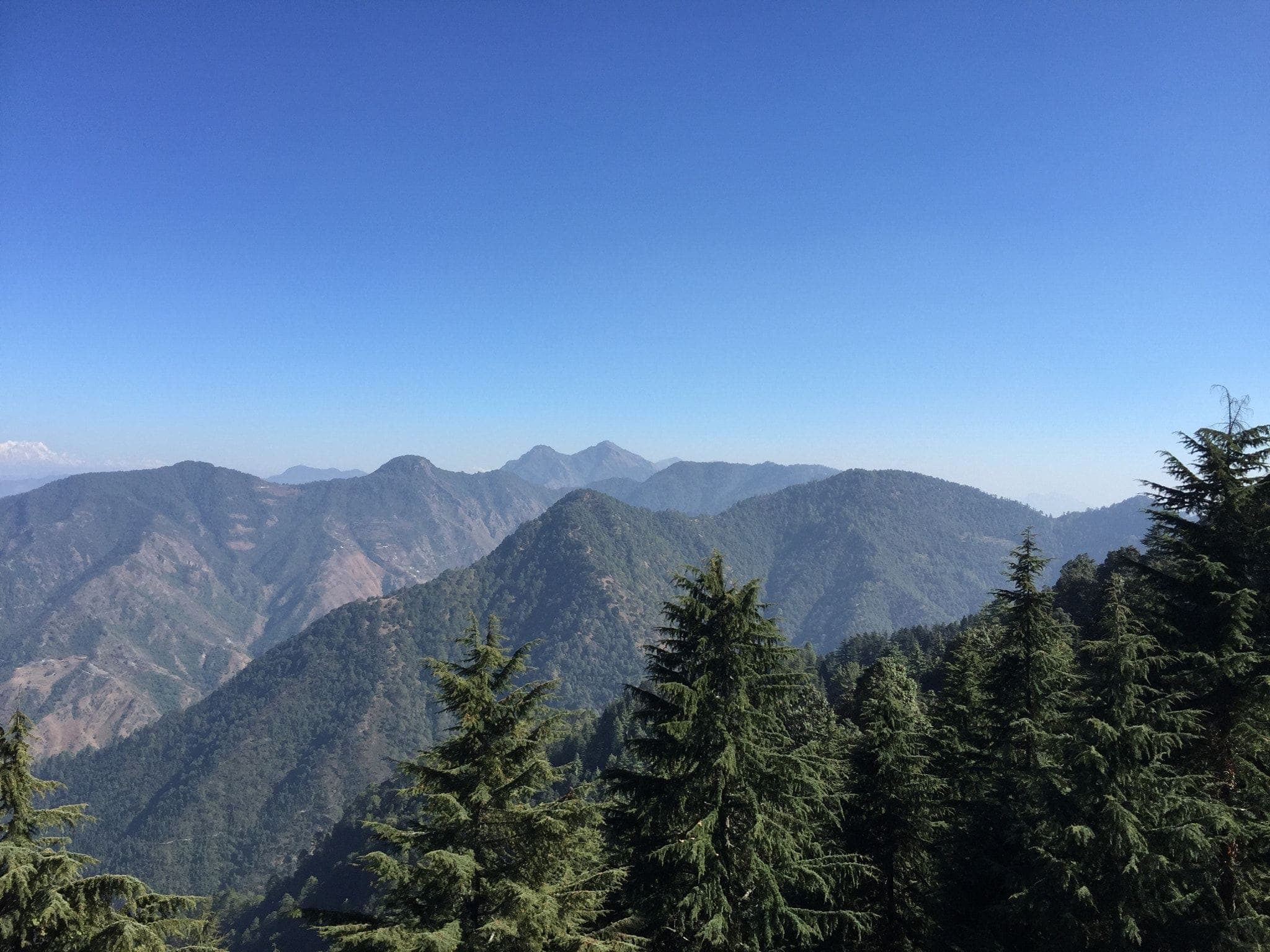 Forested Himalayan ridges fading into the distance from Mussoorie under a clear sky
